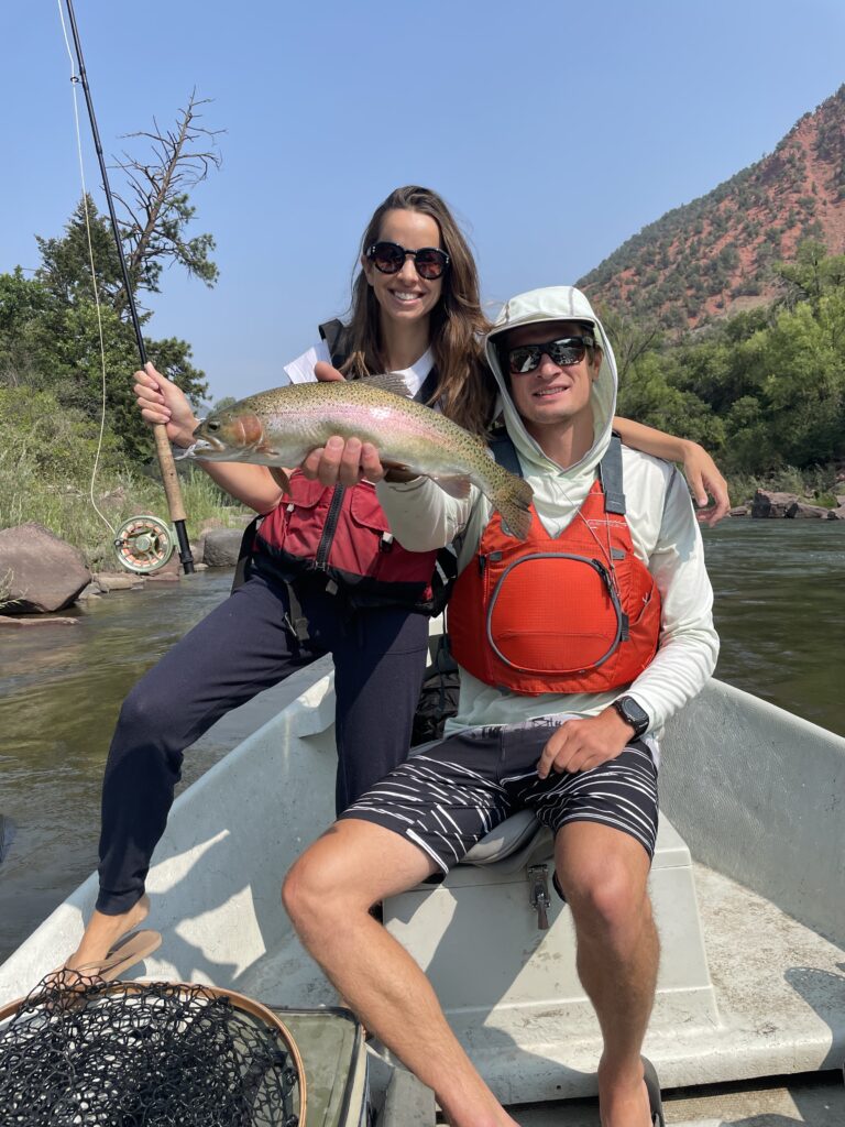 Colorado fly fishing guides assisting anglers holding brown trout on the river