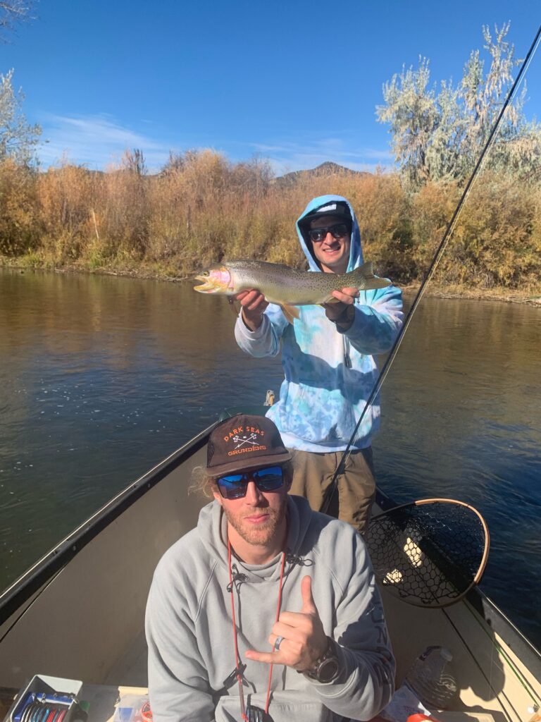 Colorado fly fishing guides with anglers holding trout on a drift boat