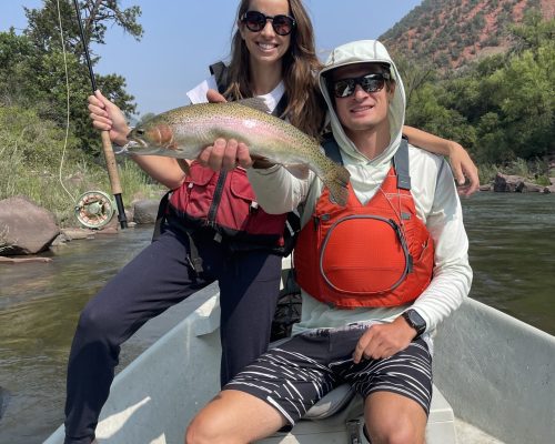 Colorado fly fishing guides assisting anglers holding brown trout on the river