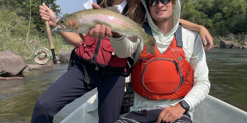 Colorado fly fishing guides assisting anglers holding brown trout on the river