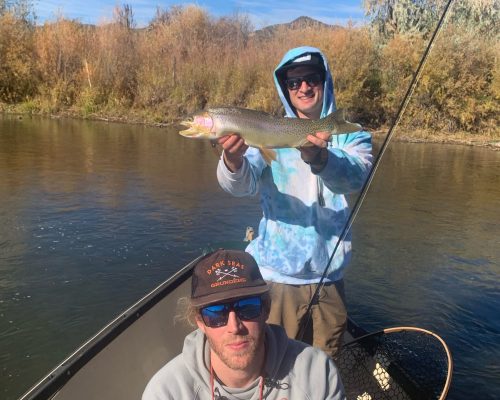 Colorado fly fishing guides with anglers holding trout on a drift boat
