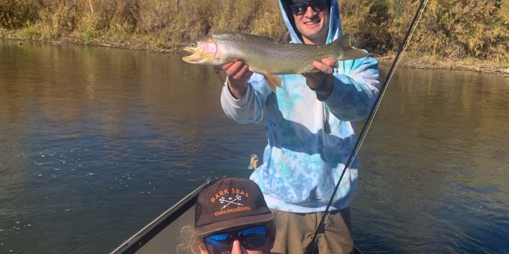 Colorado fly fishing guides with anglers holding trout on a drift boat